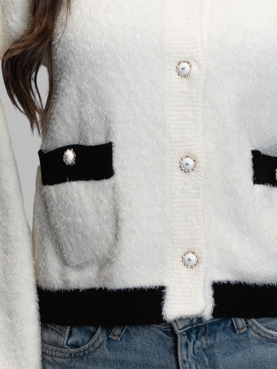 Пухкава плетена жилетка с контрастни черни детайли и декоративни копчета